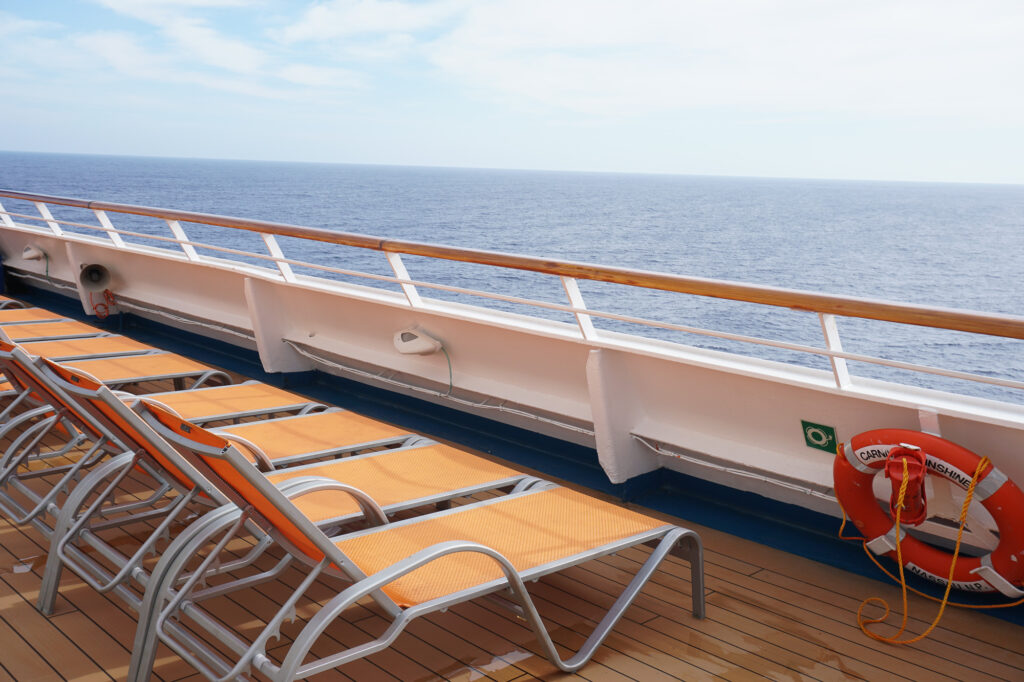 row of orange lounge chairs on cruise ship with view of ocean