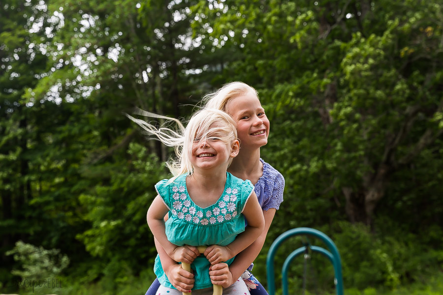 two girls on a seesaw with trees behind
